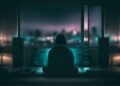 Listener experiencing ambient music through speakers in a dark room at night