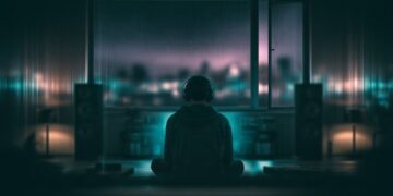 Listener experiencing ambient music through speakers in a dark room at night