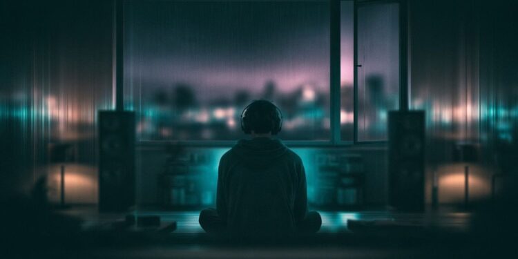 Listener experiencing ambient music through speakers in a dark room at night